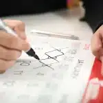 Tangan menyusun kalender pernikahan di meja dengan kotak cincin dan buku catatan